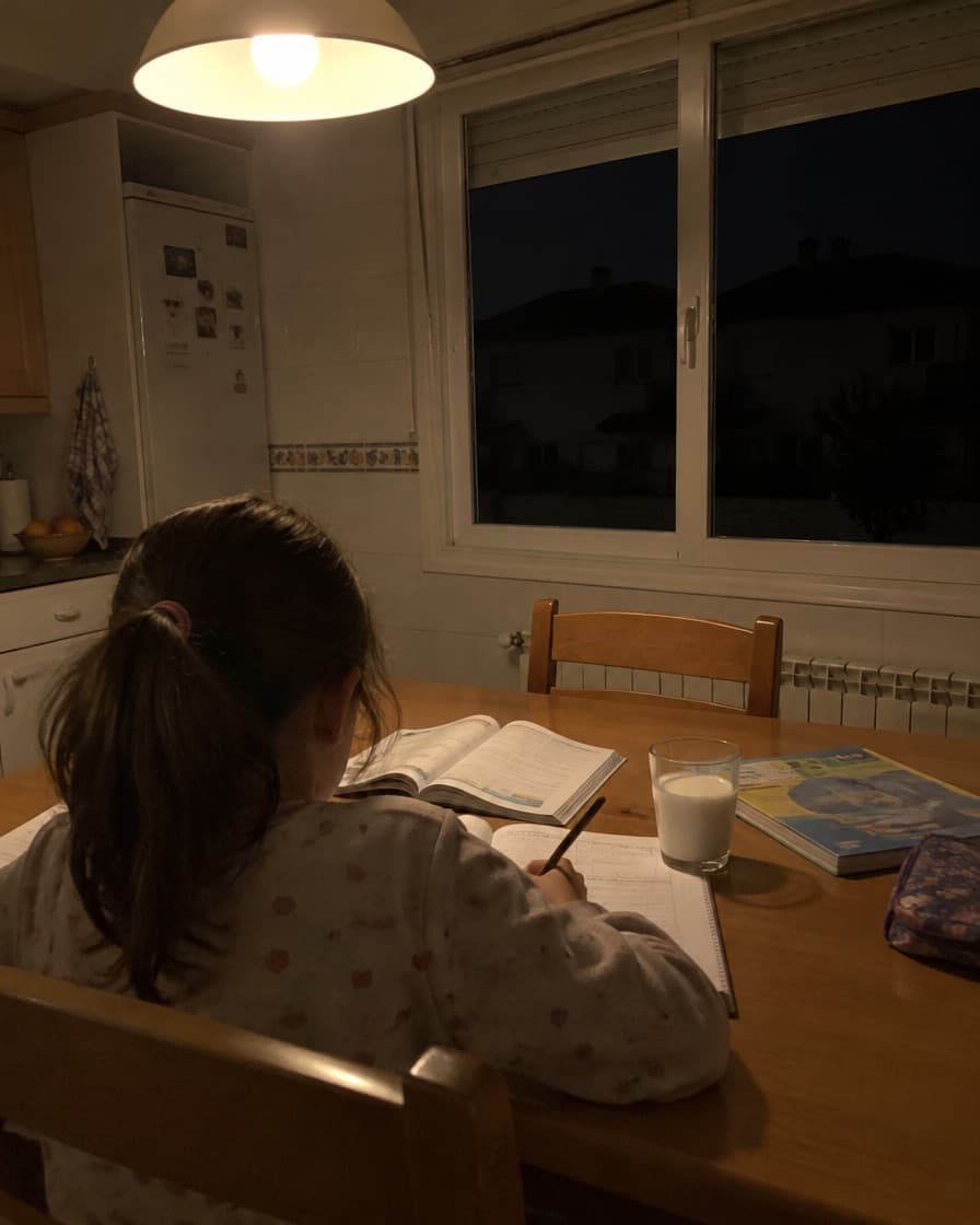 Niña haciendo los deberes bajo una lámpara encendida mientras la calle está a oscuras por un apagón